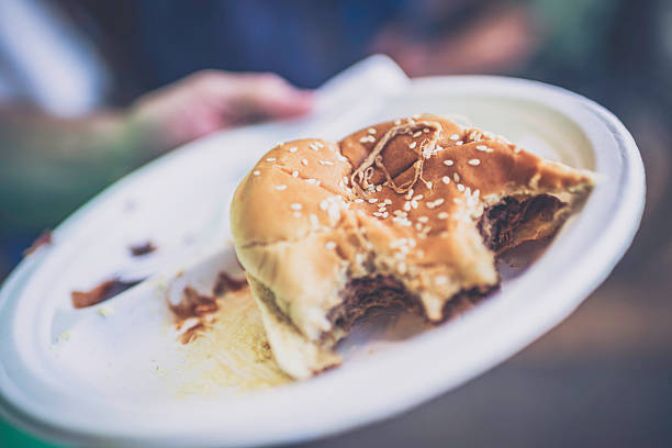 Shot of young smiling chef serving tasty burgers from the window of his food van. Focus is on the burgers.