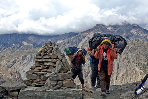 Dolpo, Nepal - September 16, 2011: Porters with heavy load walking across mountain pass in Upper Dolpo restricted area.