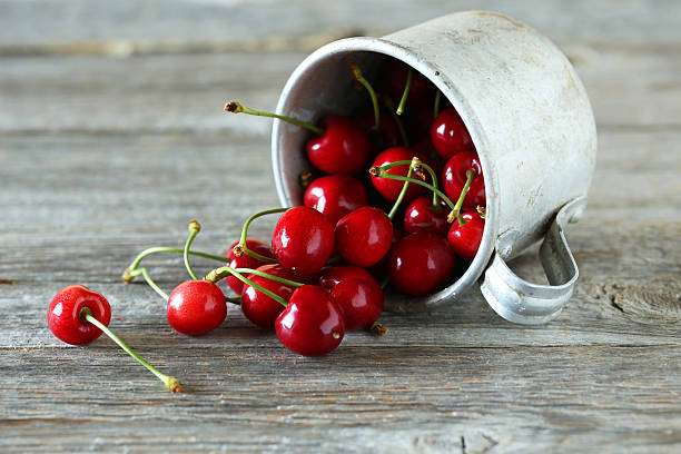 istock Ripe cherries in cup on grey wooden background 477543642