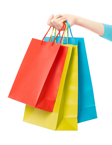 Woman hand holding three shopping bags in red, yellow, and blue color isolated on white, clipping path included