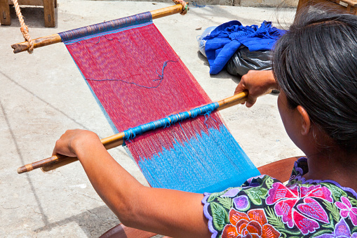 San Lorenzo Zinacantan, Mexico - May 10, 2014: Indigenous Tzotzil women weaving a traditional Huipil at the loom. San Lorenzo Zinacantan is a small village in the southern part of the Central Chiapas highlands in the Mexican state of Chiapas.