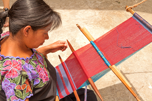 San Lorenzo Zinacantan, Mexico - May 10, 2014: Indigenous Tzotzil women weaving a traditional Huipil at the loom. San Lorenzo Zinacantan is a small village in the southern part of the Central Chiapas highlands in the Mexican state of Chiapas.