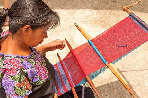 Mexican woman weaving in a traditonal way San Lorenzo Zinacantan, Mexico - May 10, 2014: Indigenous Tzotzil women weaving a traditional Huipil at the loom. San Lorenzo Zinacantan is a small village in the southern part of the Central Chiapas highlands in the Mexican state of Chiapas. loom photos stock pictures, royalty-free photos & images