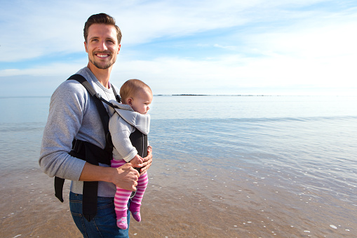 Father carrying his baby daughter along the beach