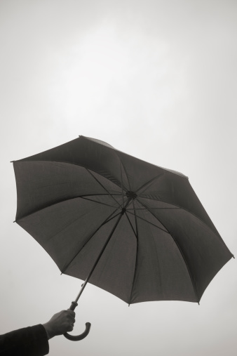 Silhouette of a hand Holding an Umbrella with moody sky background and copy space