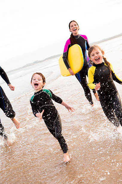 famiglia godendo il surf - wading child water sport clothing foto e immagini stock