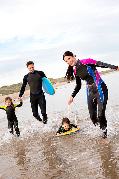 famiglia di surfisti - wading child water sport clothing foto e immagini stock