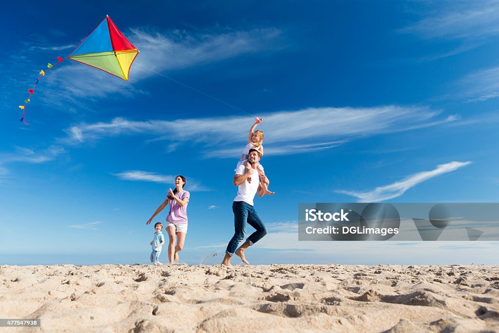 Family on the Beach Flting a Kite Family of four flying a kite on the beach Family Stock Photo
