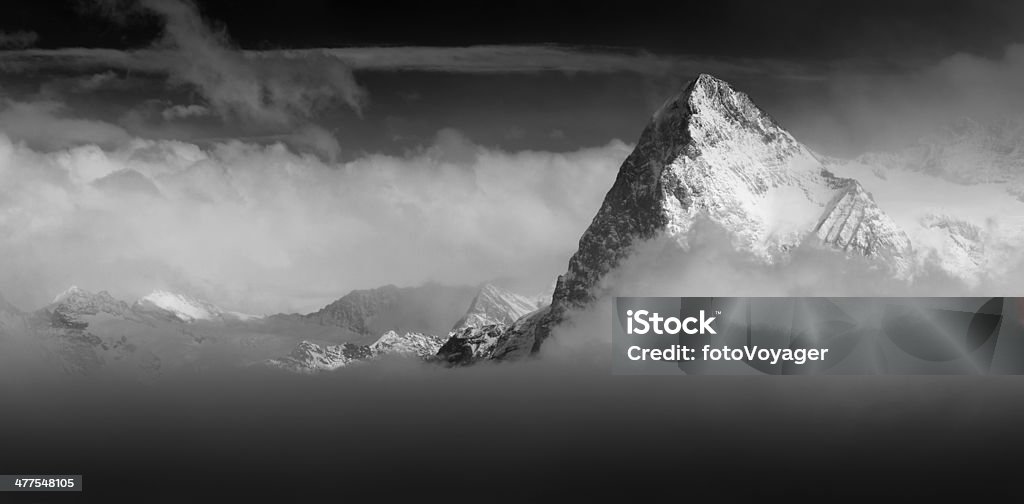 The Eiger North Face Switzerland Alps rising above the clouds The iconic North Face of the Eiger (3970m) rising above the clouds in this dramatic monochrome panoramic vista across the Bernese Alps of Switzerland. ProPhoto RGB profile for maximum color fidelity and gamut. North Face - Eiger Mountain Stock Photo