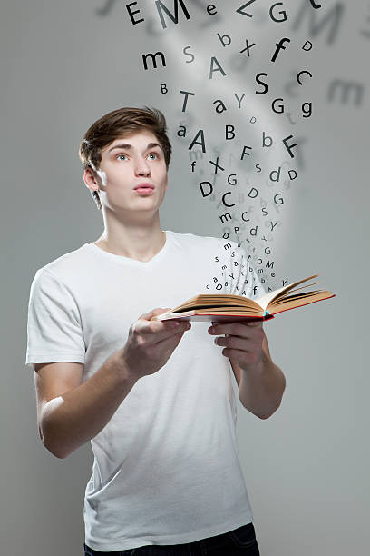 istock Young man holding a book with alphabet letters 477548160