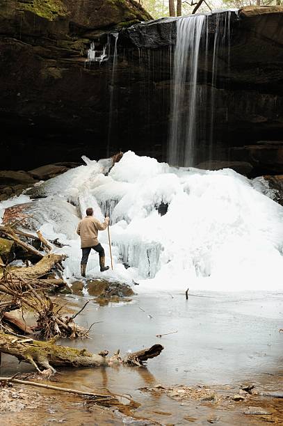 istock Man hiking up to frozen water below waterfall 477549269