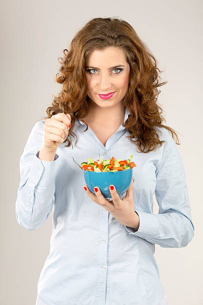 istock Female model hold green salad in blue bowl 477549557