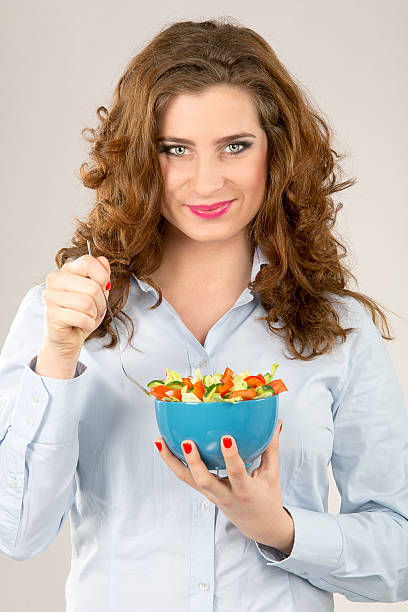 istock Female model hold green salad in blue bowl 477549561