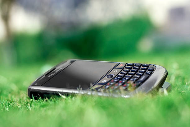 New Delhi, India – November 30, 2010: Close up View of the Blackberry Curve 8900 Smartphone Lying Dawn in Park with Shallow Depth of Field.