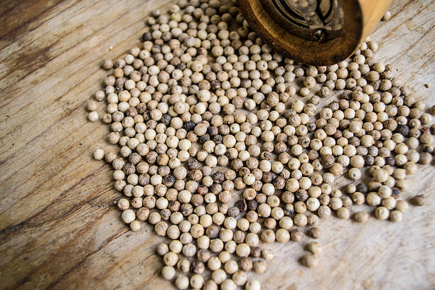 istock Pepper mill and pepper on wooden background 477555715