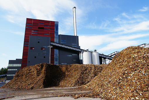 bio power plant with storage of wooden fuel (biomass) against blue sky