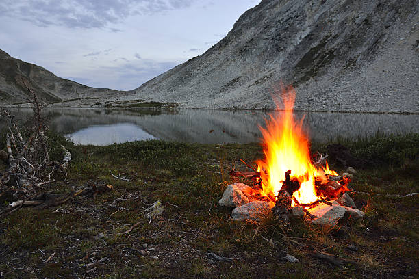 istock fire near the mountain lake at night 477564869