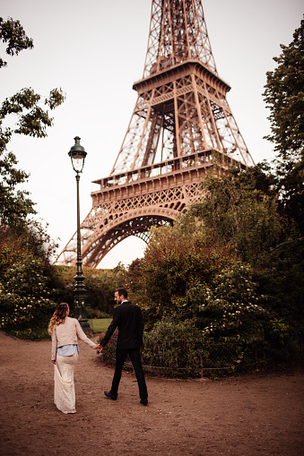 Romantic walk of a young, married couple in the gardens around Eiffel Tower (Paris, France).