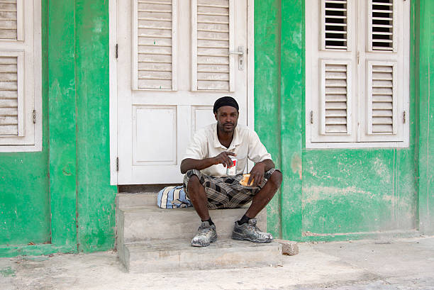 Willemstad, Curacao - March 23, 2015: Young man sitting on some steps having his lunch break.