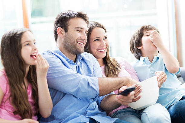 istock Family watching TV and eating popcorn 477568718