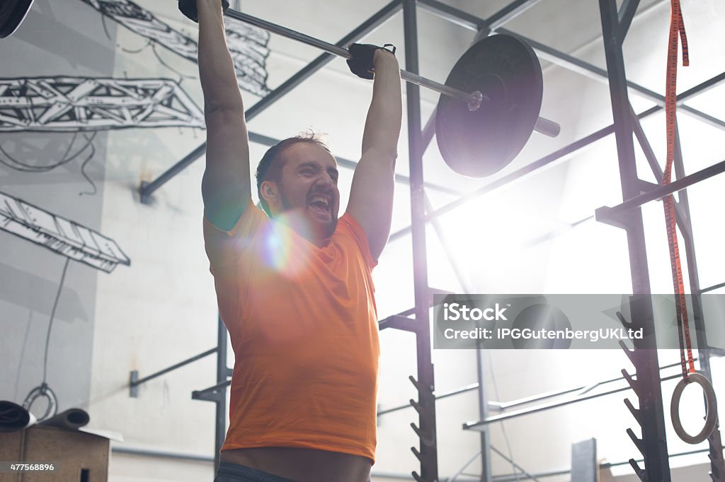 Working out at the Gym Dedicated man lifting barbell in gym gym 2015 Stock Photo