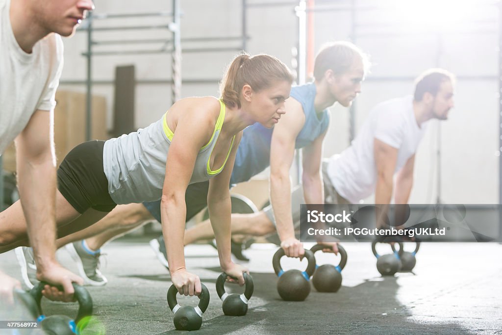 Working out at the Gym Determined people doing pushups with kettlebells at gym gym 20-24 Years Stock Photo