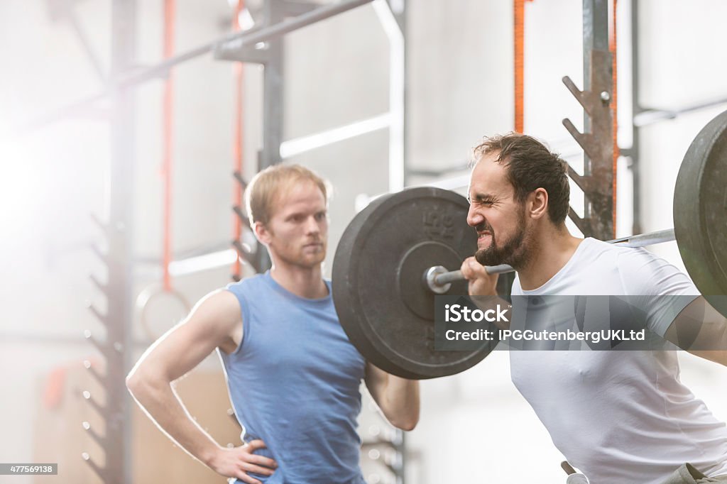Working out at the Gym Man assisting friend in lifting barbell at gym gym 20-24 Years Stock Photo
