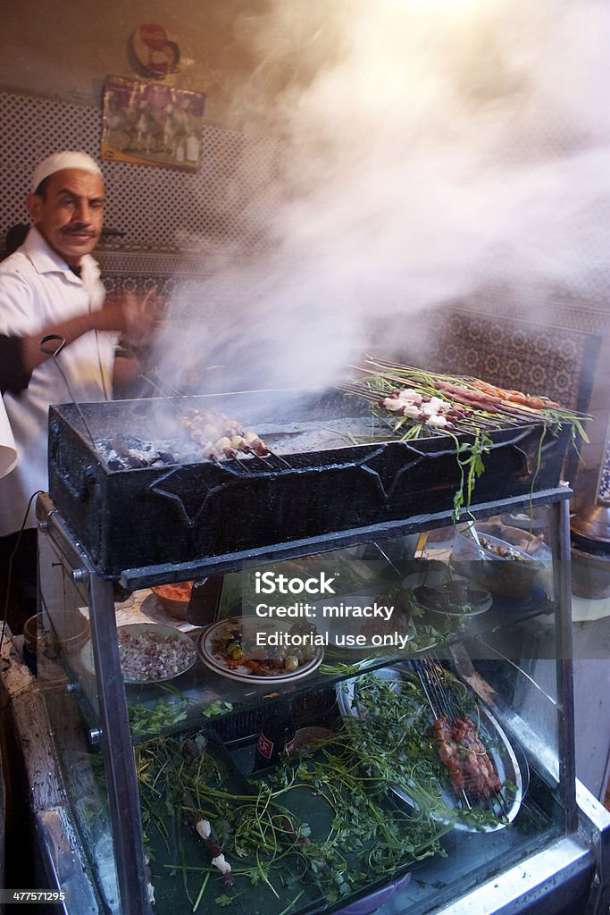 Brochette food stand in Marrakech Marrakech, Morocco - February 10, 2013: Street food stand with brochette, its vendor cooking and smoke coming out of it in Marrakech, Morocco Marrakesh Stock Photo