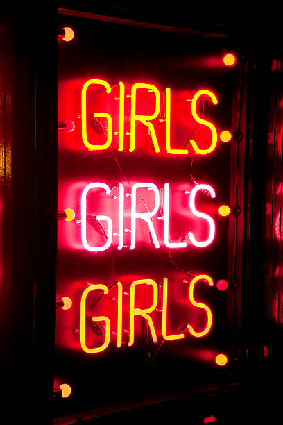 Neon strip club sign A glowing red neon striptease sign on a building at night. strip club stock pictures, royalty-free photos & images