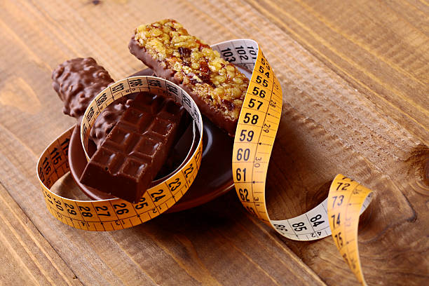 delicioso chocolate bares e pé de moleques com uma fita de medição - chocolate candy unhealthy eating eating food and drink - fotografias e filmes do acervo