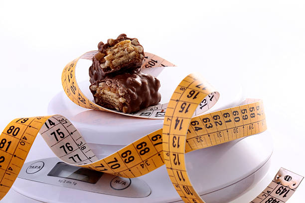istock Sweet chocolate bar broken in half with a measuring tape 477585156