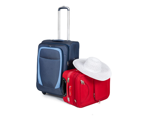Blue and red Travel suitcases and hat isolated on white background. Color image in horizontal orientation