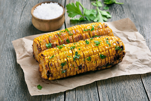 Grilled corn cobs on paper over rustic table