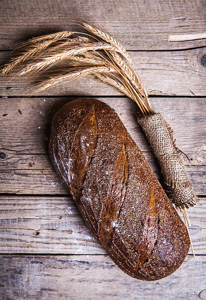 istock Rustic bread and wheat on old vintage planked wood table. 477586918