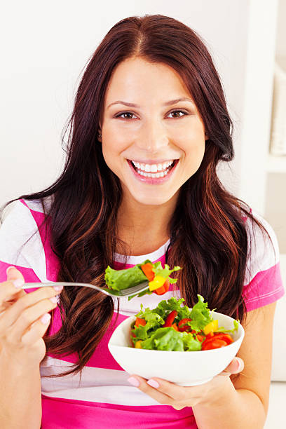 istock Young woman eating a salad 477589047