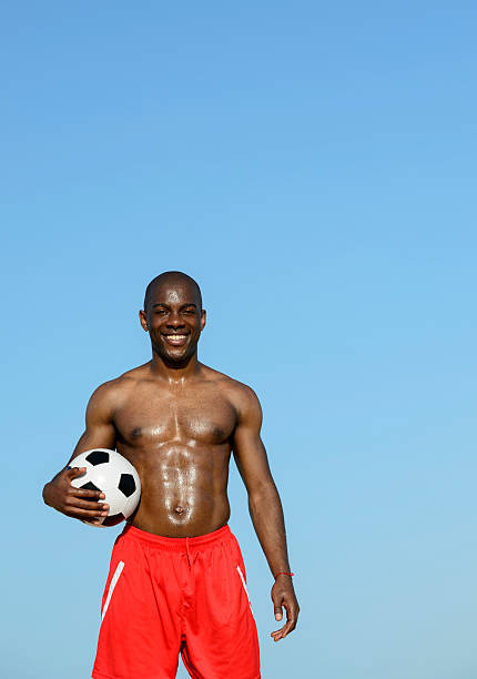 istock Young Man Playing Football On The Beach 477591195