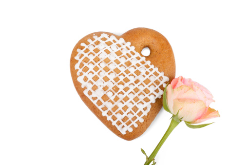 Romantic gift: Ginger heart-shaped cookie with beautiful small rose isolated on white background