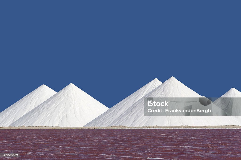 White Salt and Pink Water Heaps of salt at the salt pans behind the pink colored sea. Agricultural Machinery Stock Photo