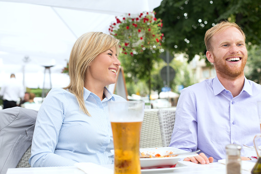 Happy businessman and businesswoman sitting at outdoor restaurant