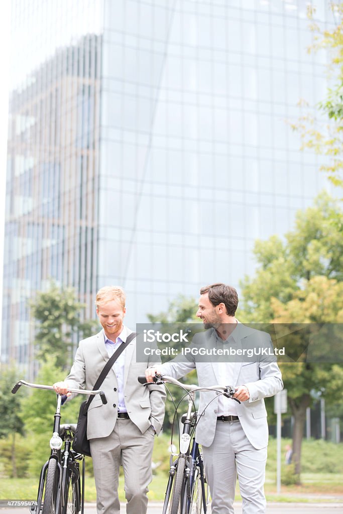 Business After Hours Businessmen with bicycles walking against office building 20-24 Years Stock Photo
