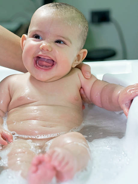 istock baby girl smiles during bathing supported by mom 477597447