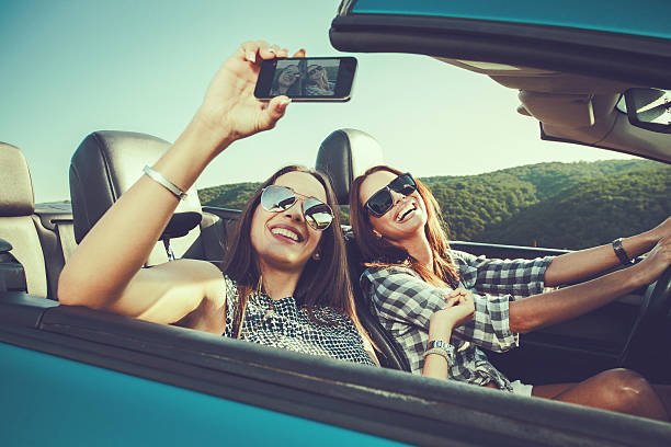 istock Two attractive young women dtaking selfe in a convertible car 477598246