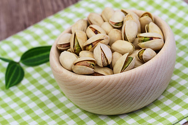 istock Pistachio nuts in wooden bowl on checkered cloth 477598362