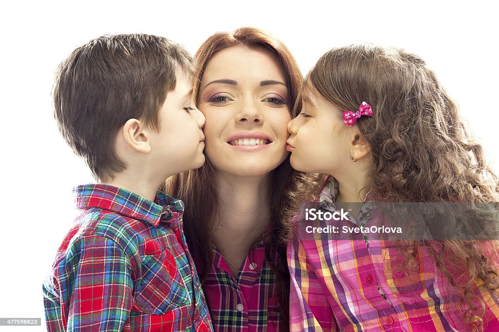 Happy mother kissed by her daughter and son Portrait of children kissing her mother with flowers. Mothers day concept. Family holiday. Isolated white background Adult Stock Photo