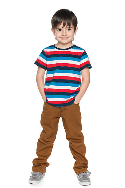 Portrait of little boy over white background. Teenage boy standing isolated on white looking at camera with blank facial expression. Horizontal composition. Boy has got short blond hair. He is wearing a striped t-shirt. Studio shot.