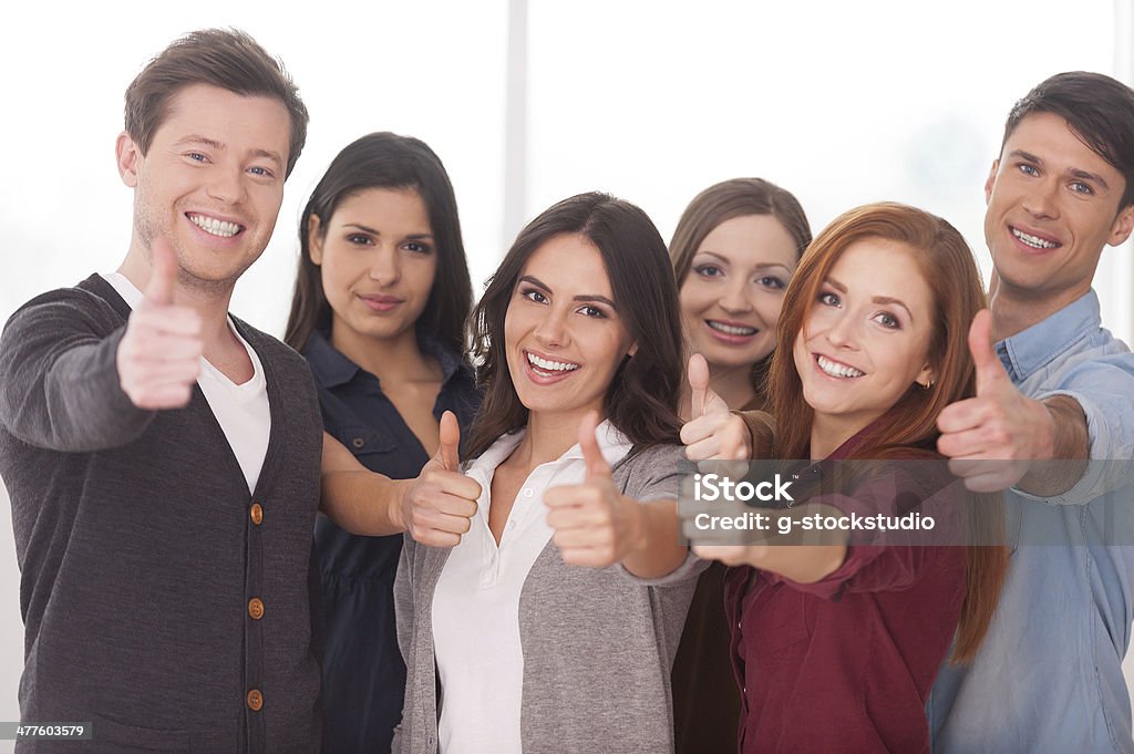 We are successful team! Group of cheerful young people standing close to each other and gesturing Group Of People Stock Photo