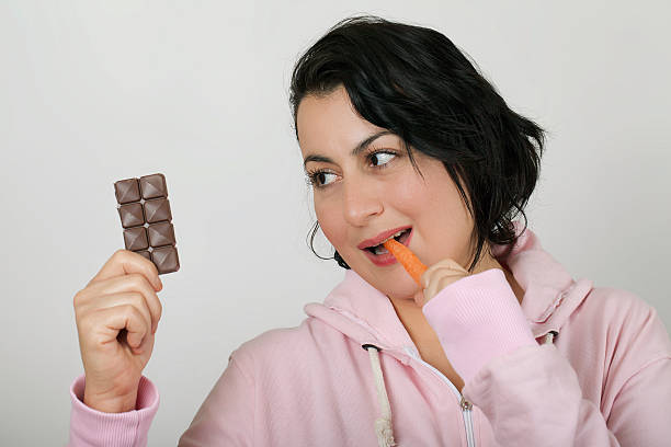 istock Woman eating Carrot and Looking Chocolate 477603699