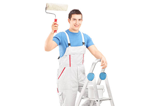 istock Male painter holding a roller and standing on ladder 477609513