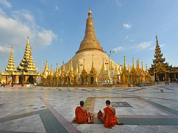 Shwedagon Pagoda Yangon, Myanmar - December 4th 2014:Two monks sit in front of the golden stupa of Shwedagon Pagoda, the most famous sight of Burma shwedagon pagoda photos stock pictures, royalty-free photos & images