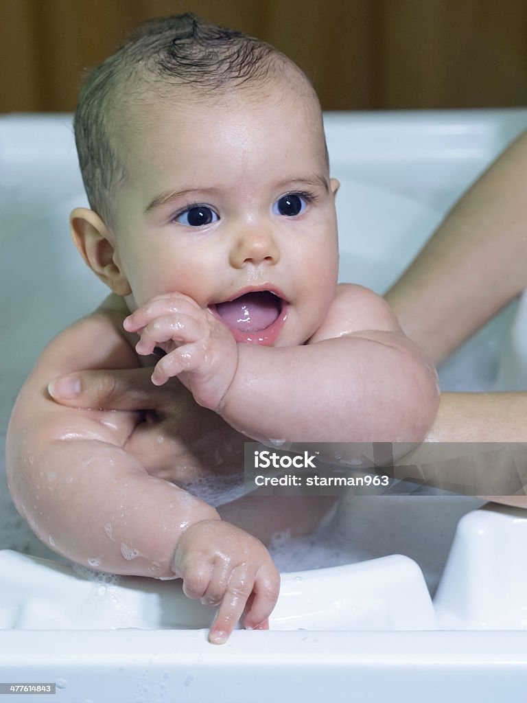 Bambina sorride durante il bagno supportati da mamma - Foto stock royalty-free di Accudire